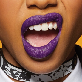 Model showing off bright purple lipstick and pearly white teeth.